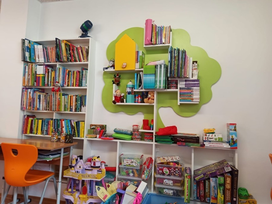 Sala de lectură cu rafturile de cărți, raftul-nor verde și mesele de lucru